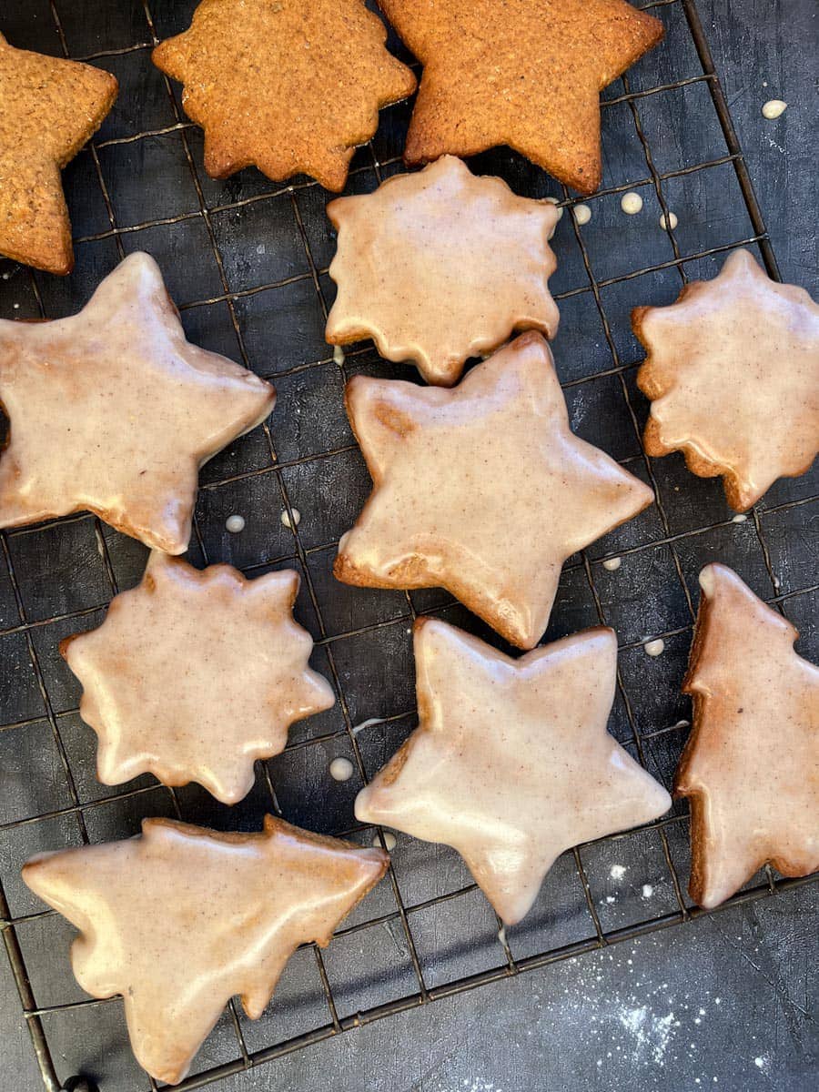 various star, Christmas tree and snowflake shaped cookies with a rum icing glaze on a black wire cooling rack.