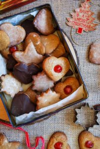 A box filled with German gingerbread cookies glazed with icing sugar, coated in chocolate and topped with glace cherries.