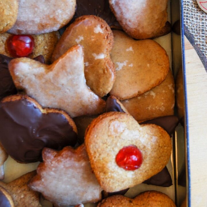 a box filled with gingerbread star and heart cookies, glazed with icing, melted chocolate and glace cherries.