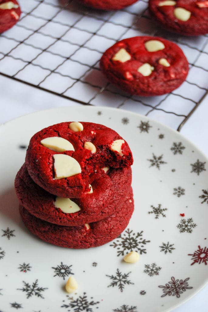 three red velvet cookies with white chocolate chunks on a white and silver star plate.