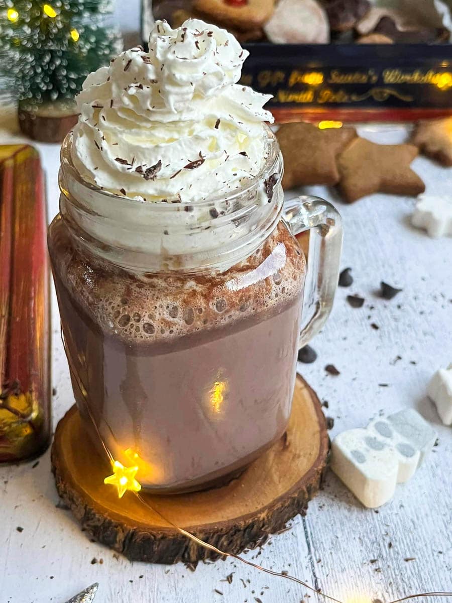 a glass mug of hot chocolate topped with whipped cream and grated chocolate.