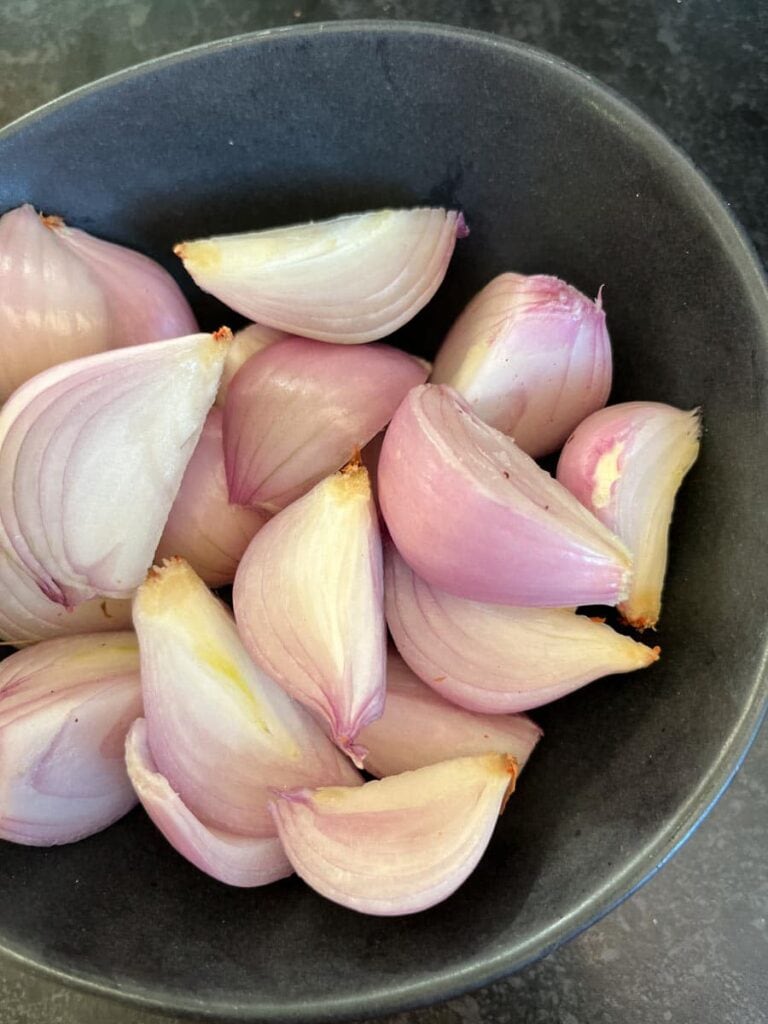 a small black bowl of peeled and halved shallots.