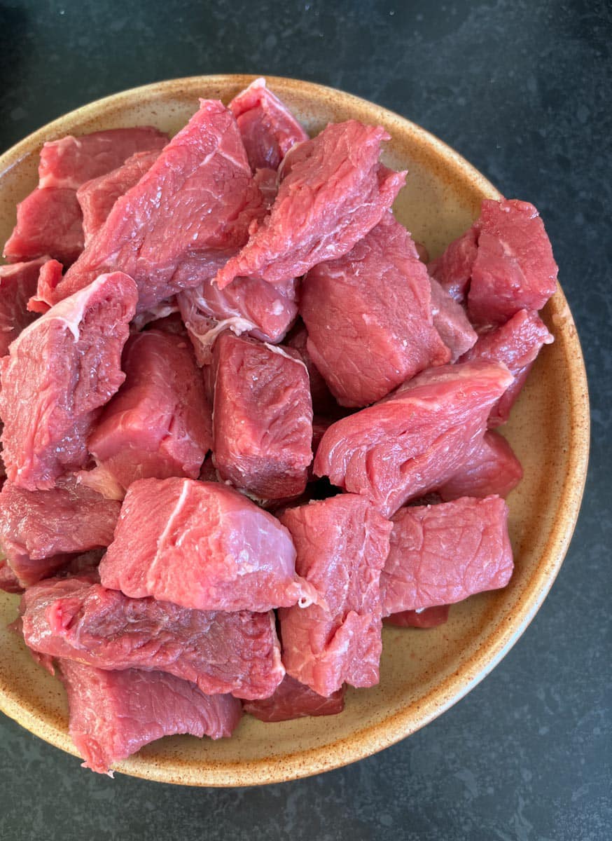 a beige stoneware bowl of diced beef.