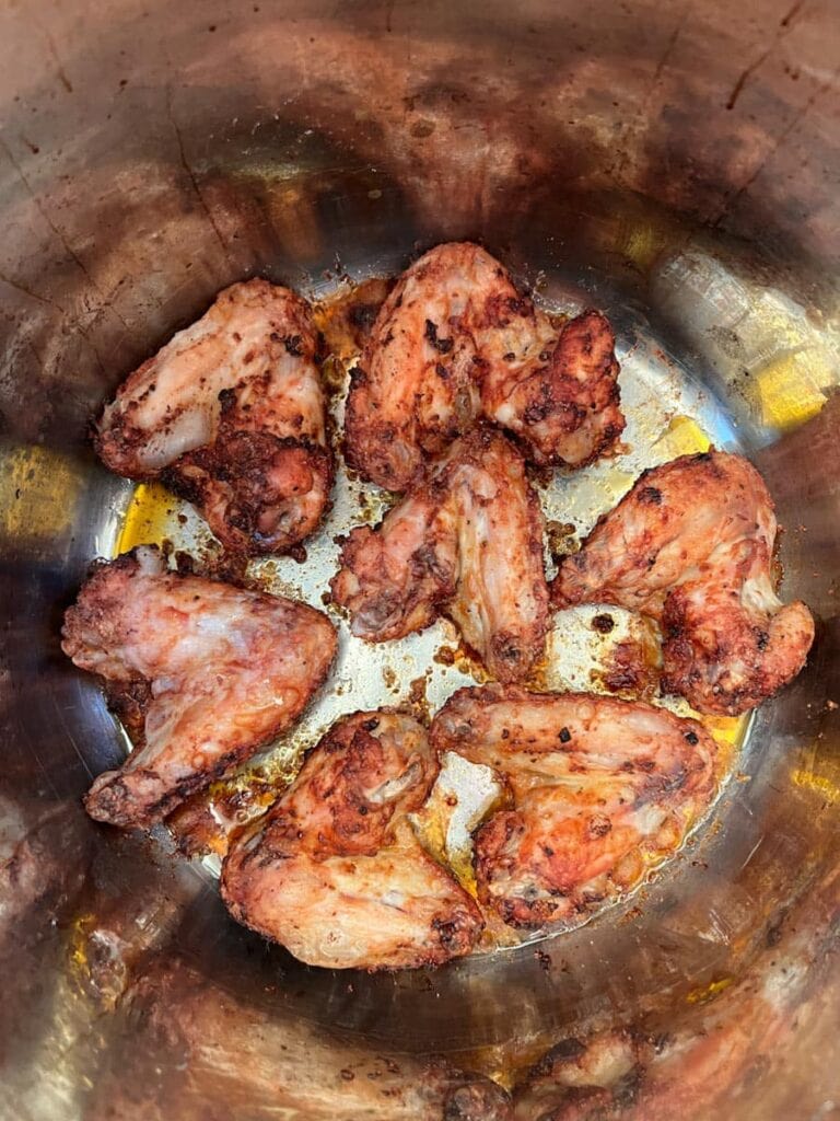 seven chicken wings being cooked in an air fryer.