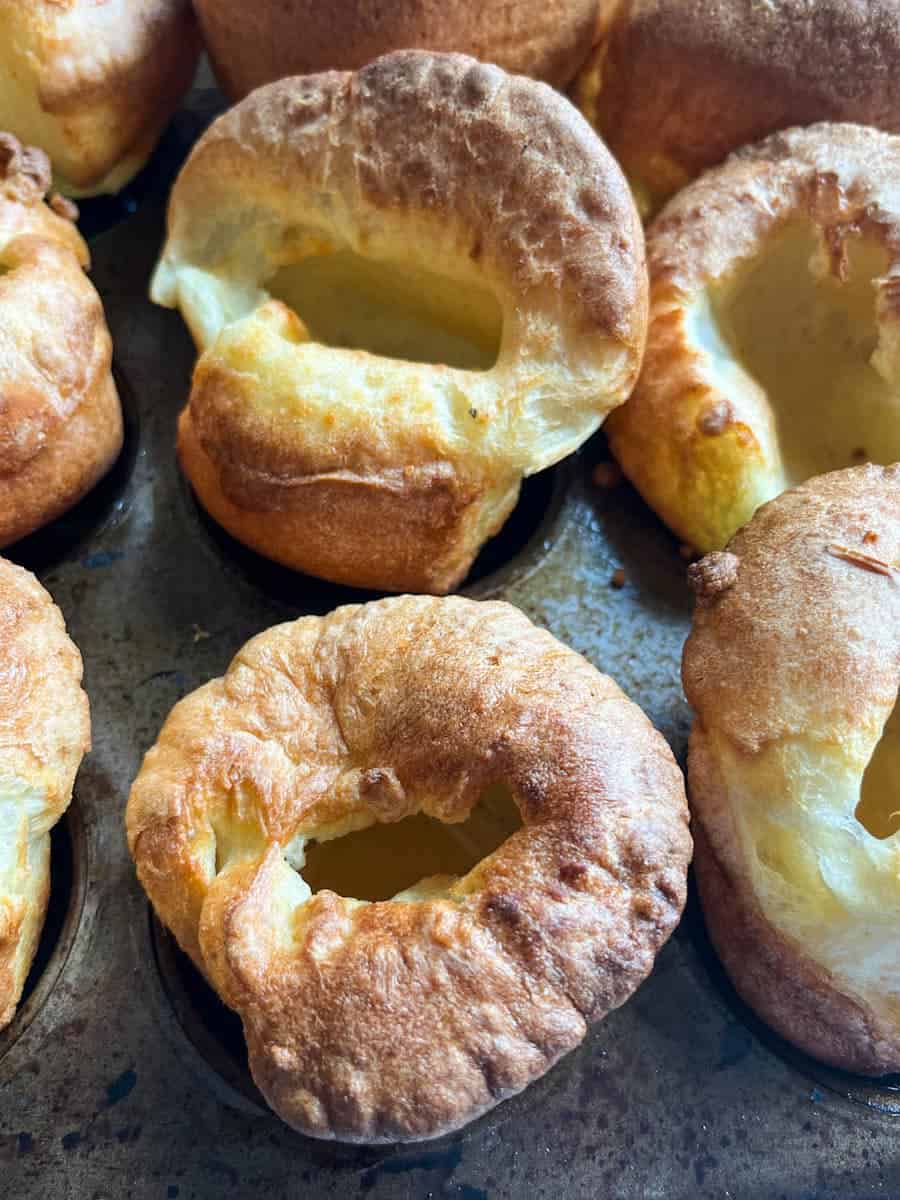 Nine Yorkshire puddings in a metal muffin tin.