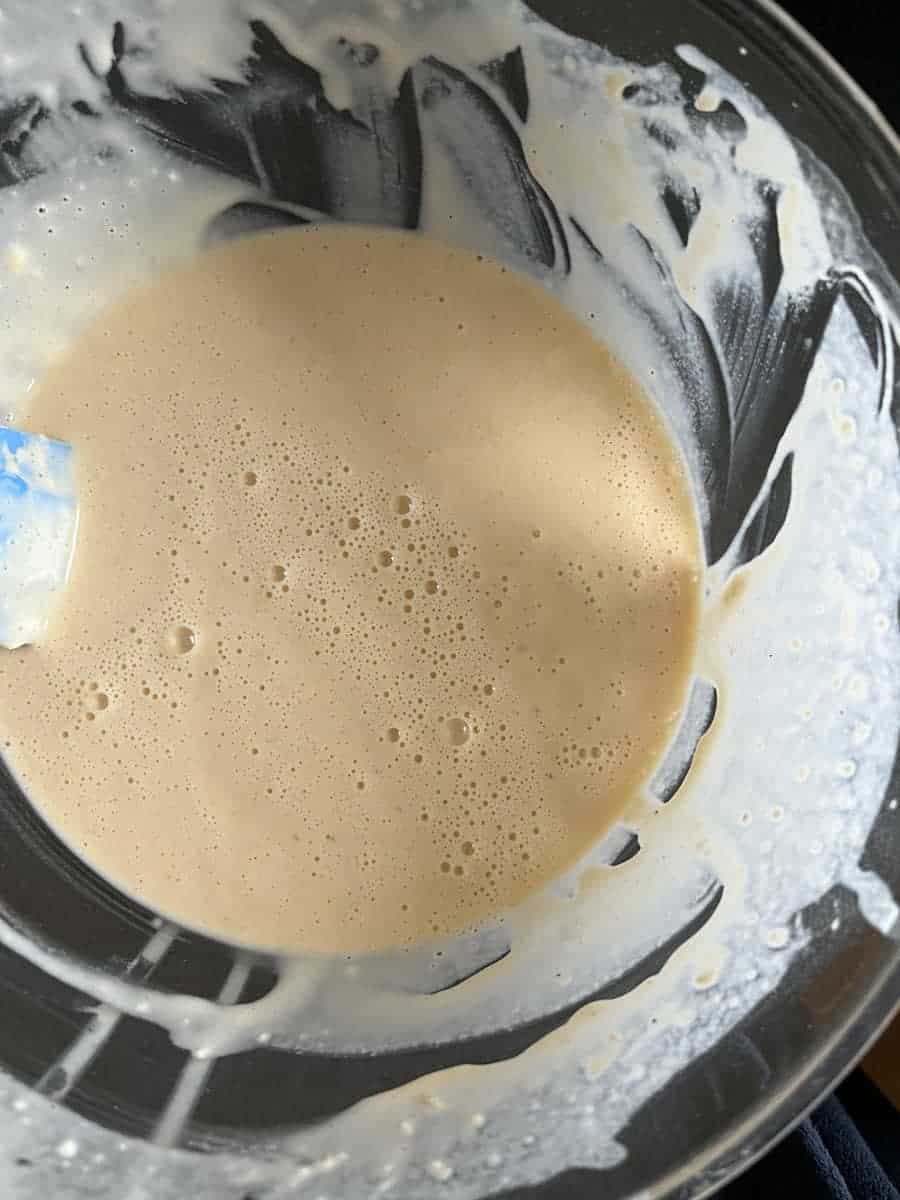 an egg, flour and milk batter in a large glass mixing bowl.