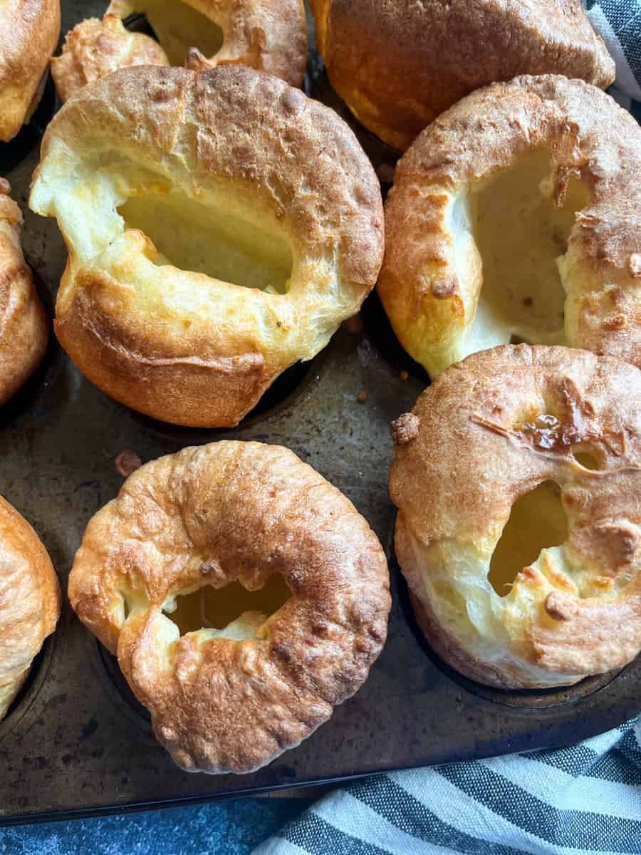 nine golden, well risen Yorkshire puddings in a metal muffin tin.