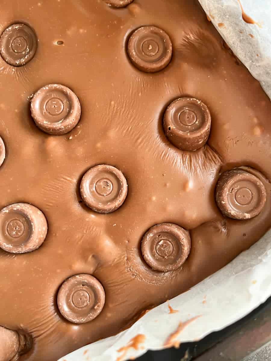 chocolate fudge topped with chocolate caramels in a square tin.