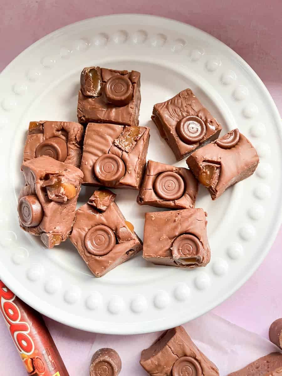 a white plate of chocolate fudge with Rolo sweets.