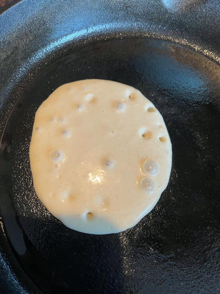 a pancake cooking in a cast iron pan.