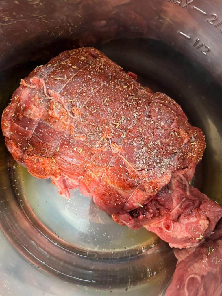 a piece of seasoned brisket beef in a silver pot.