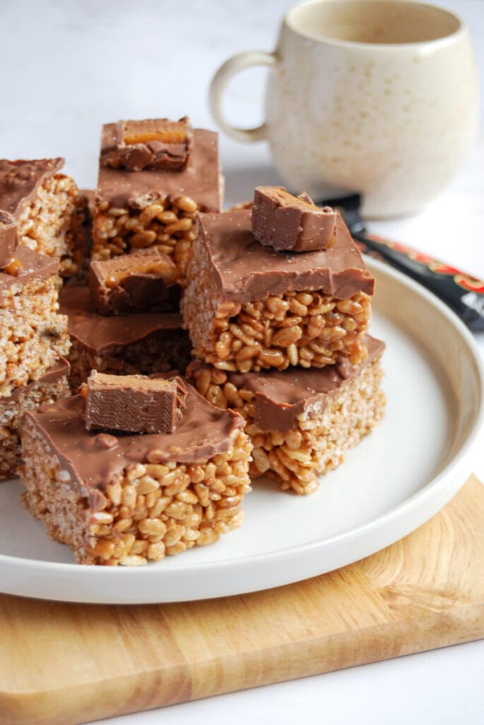 a white plate of Mars bar crispy slices topped with milk chocolate and a Mars bar slice.