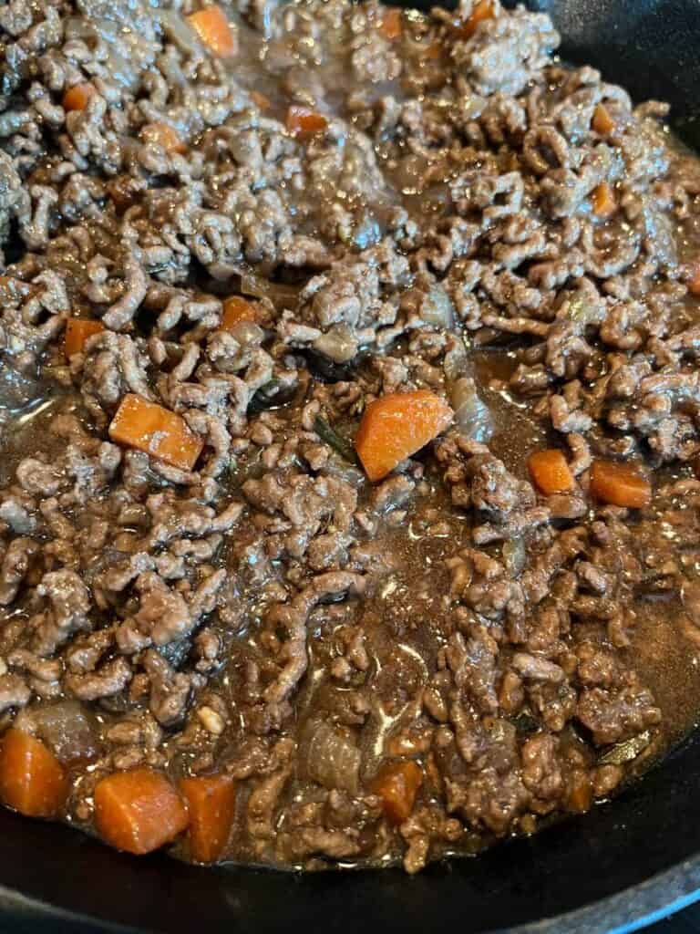 a pan of cooked minced beef and carrots in gravy.