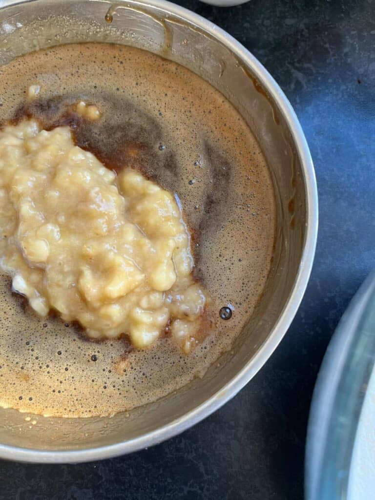 a silver bowl of mashed bananas, oil, beaten eggs and coffee.