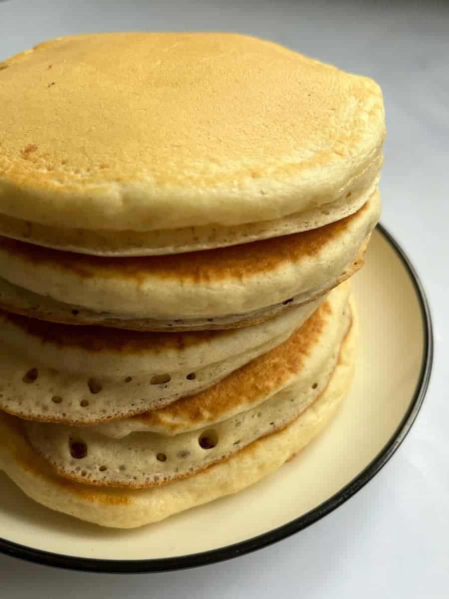 five buttermilk pancakes on a white and black plate.