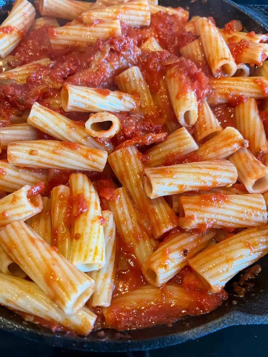 a black saucepan of rigatoni pasta in tomato sauce.