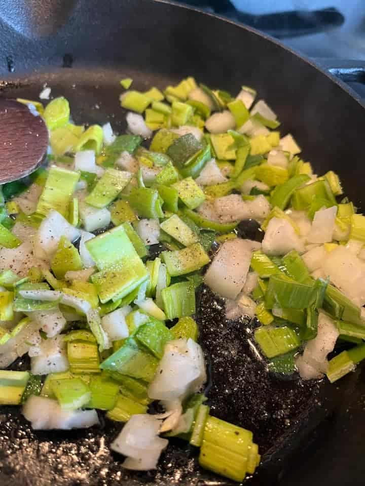 diced leeks cooking in butter and oil in a frying pan.