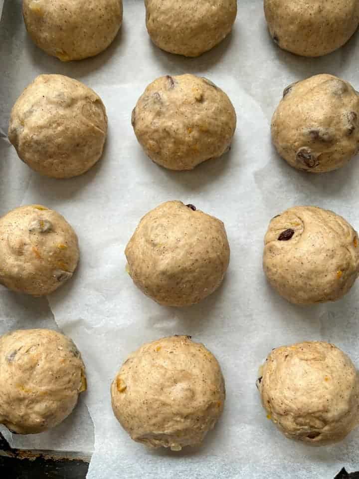 twelve pieces of fruit dough sitting on a baking tray lined with baking parchment.