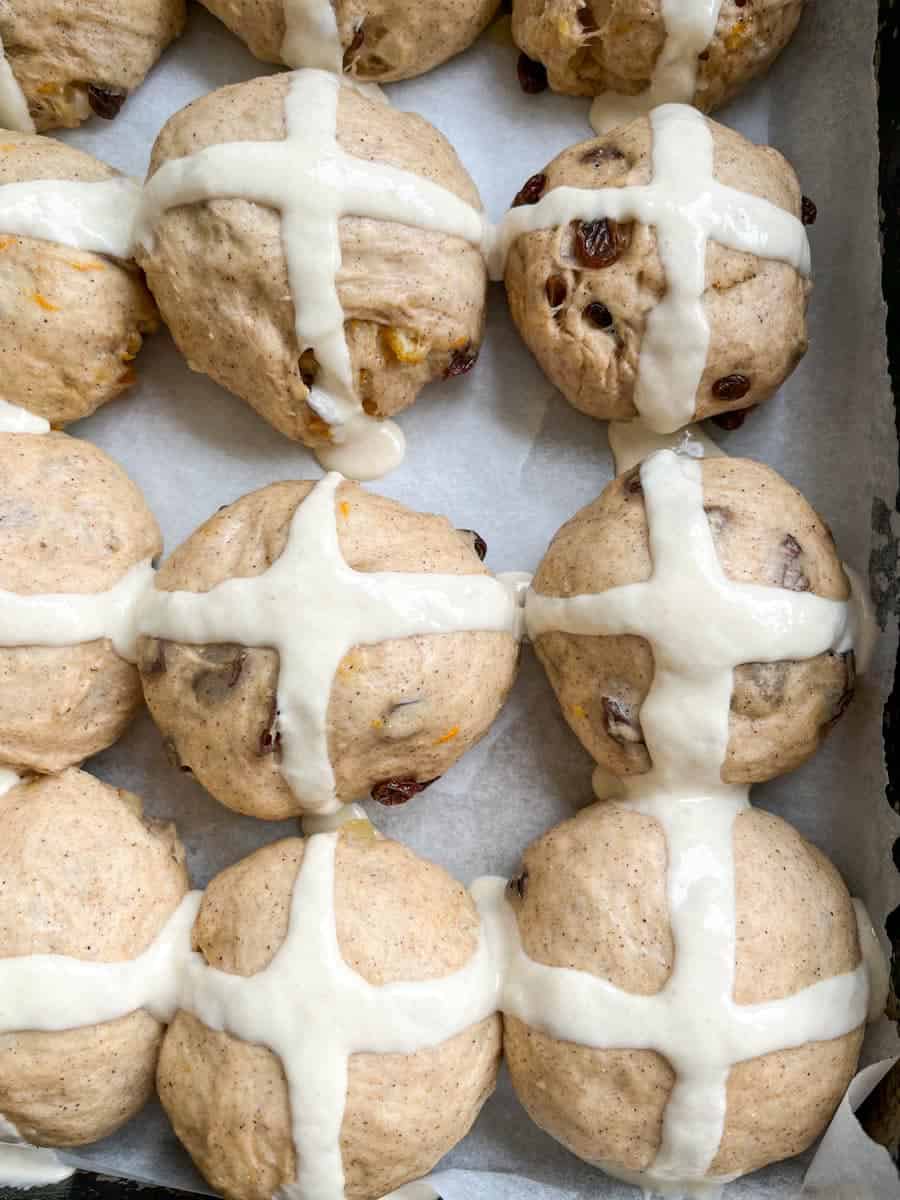 a batch of unbaked hot cross buns piped with crosses.