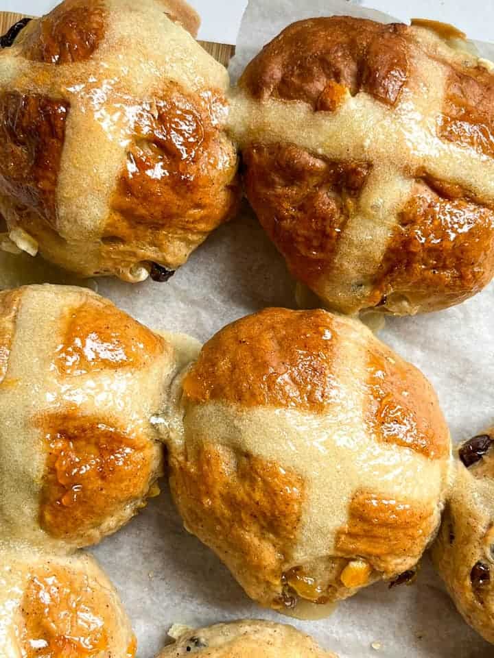 a batch of hot cross buns brushed with orange marmalade.