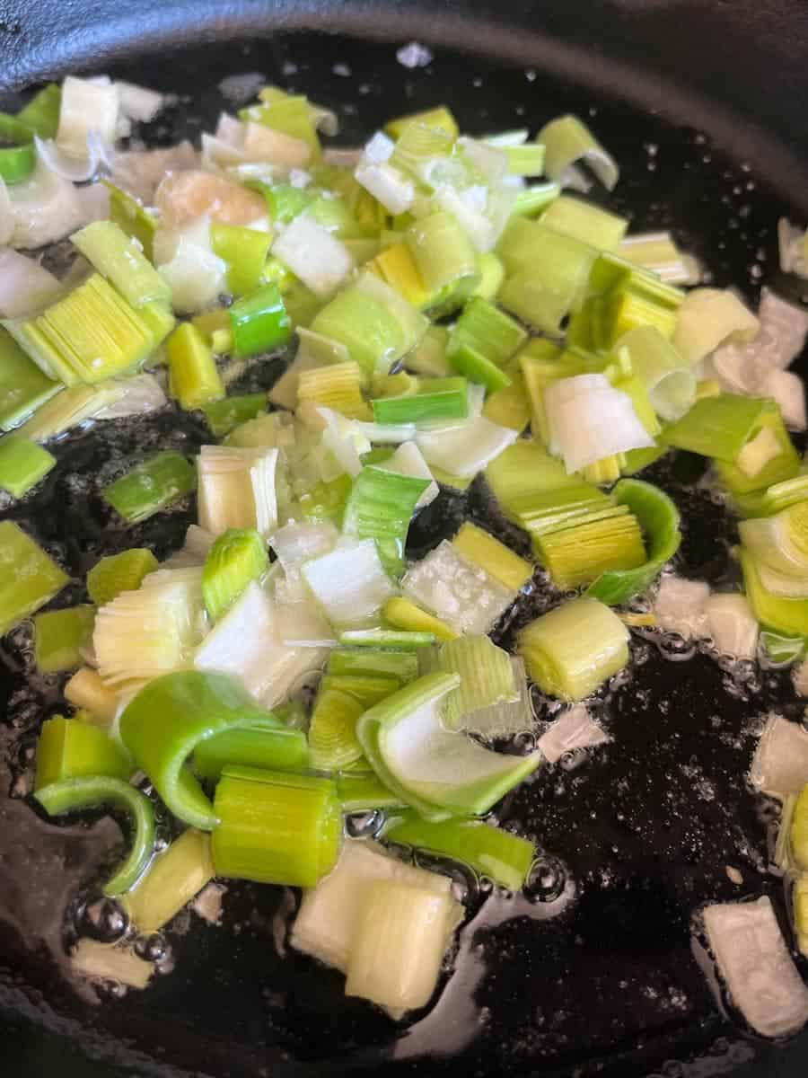 sliced leeks and garlic cooking in a saucepan.