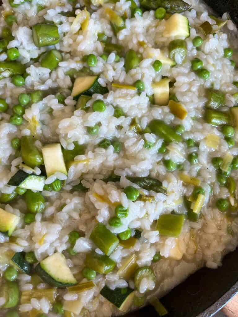 a pan of risotto with aparagus, peas, broad beans, diced courgette and sliced leeks.