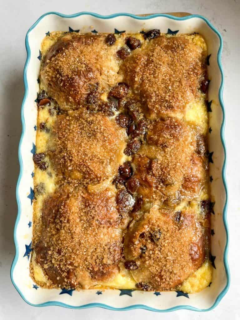 a blue and white star patterned dish of a hot cross bun bread pudding with chocolate chips and raisins.