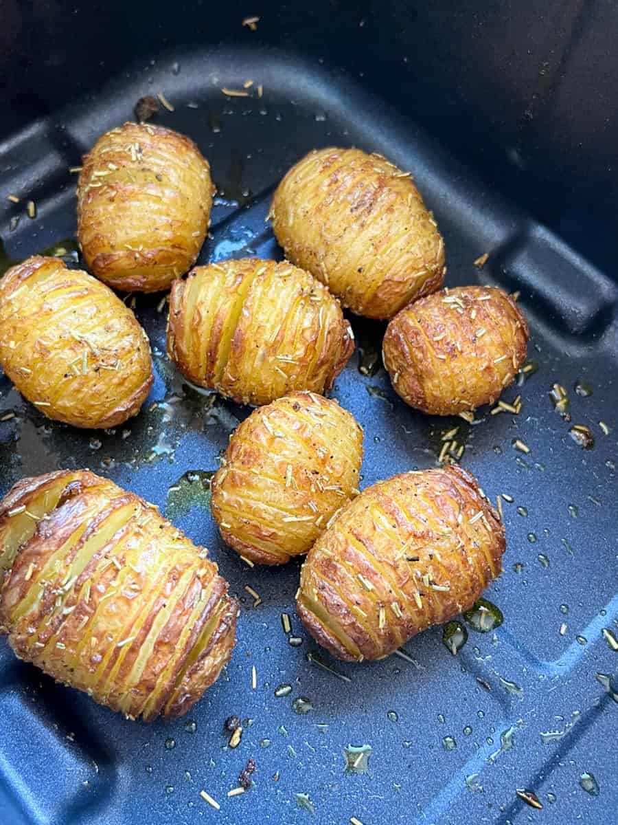 eight Hasselback potatoes in an air fryer basket.