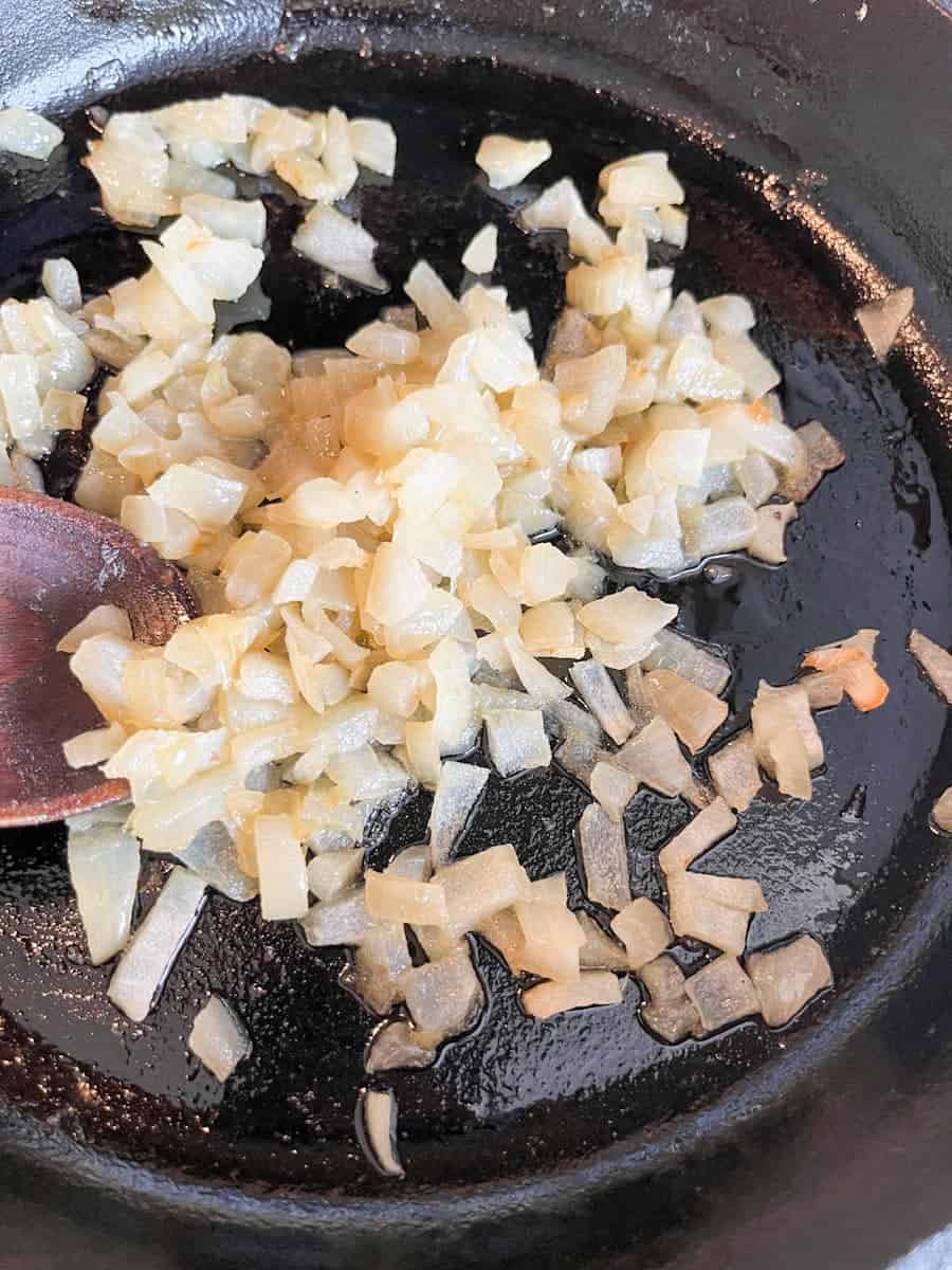 diced onions cooking in a black skillet.