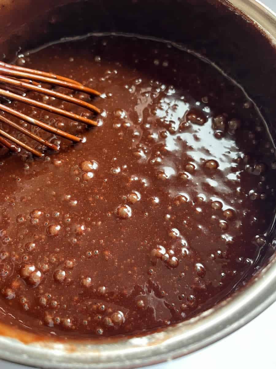 a saucepan of chocolate Guinness cake batter and a silver whisk.
