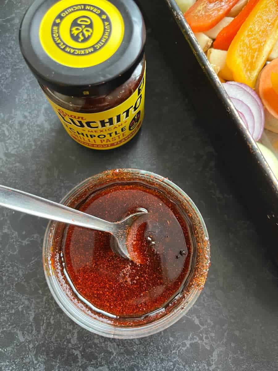a jar of chipotle chilli paste and a small pot of the chilli paste mixed with honey and oil with a silver spoon.