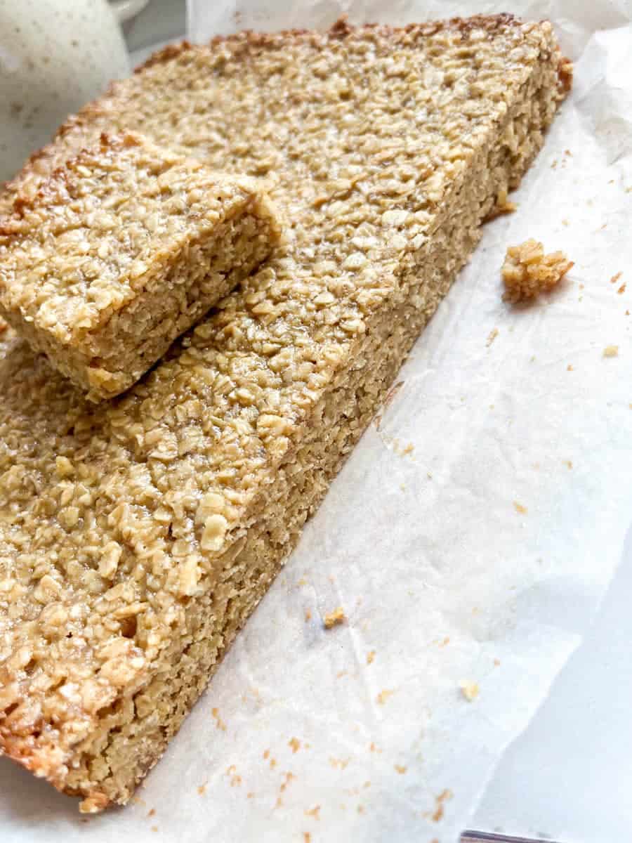 A large flapjack oat bar with a cut out piece sitting on top.