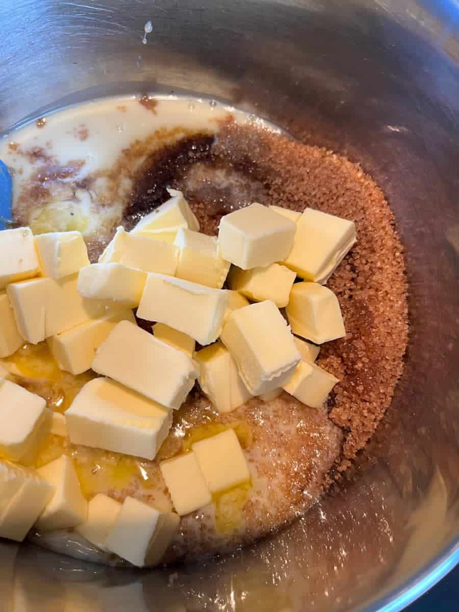 a silver saucepan of cubed butter, brown sugar, condensed milk and golden syrup slowly melting.