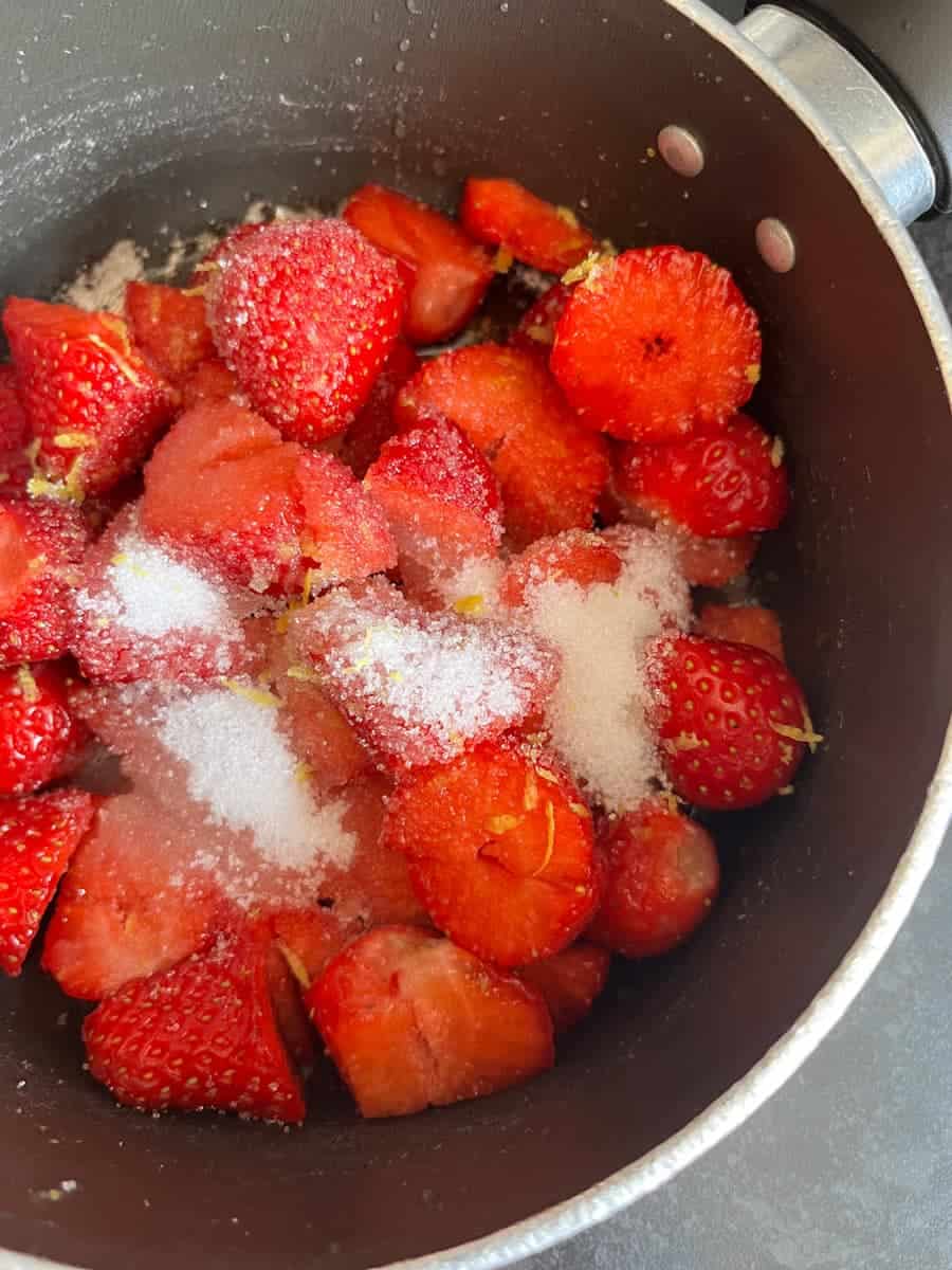 A pan of sliced strawberries sprinkled with sugar and lemon zest.