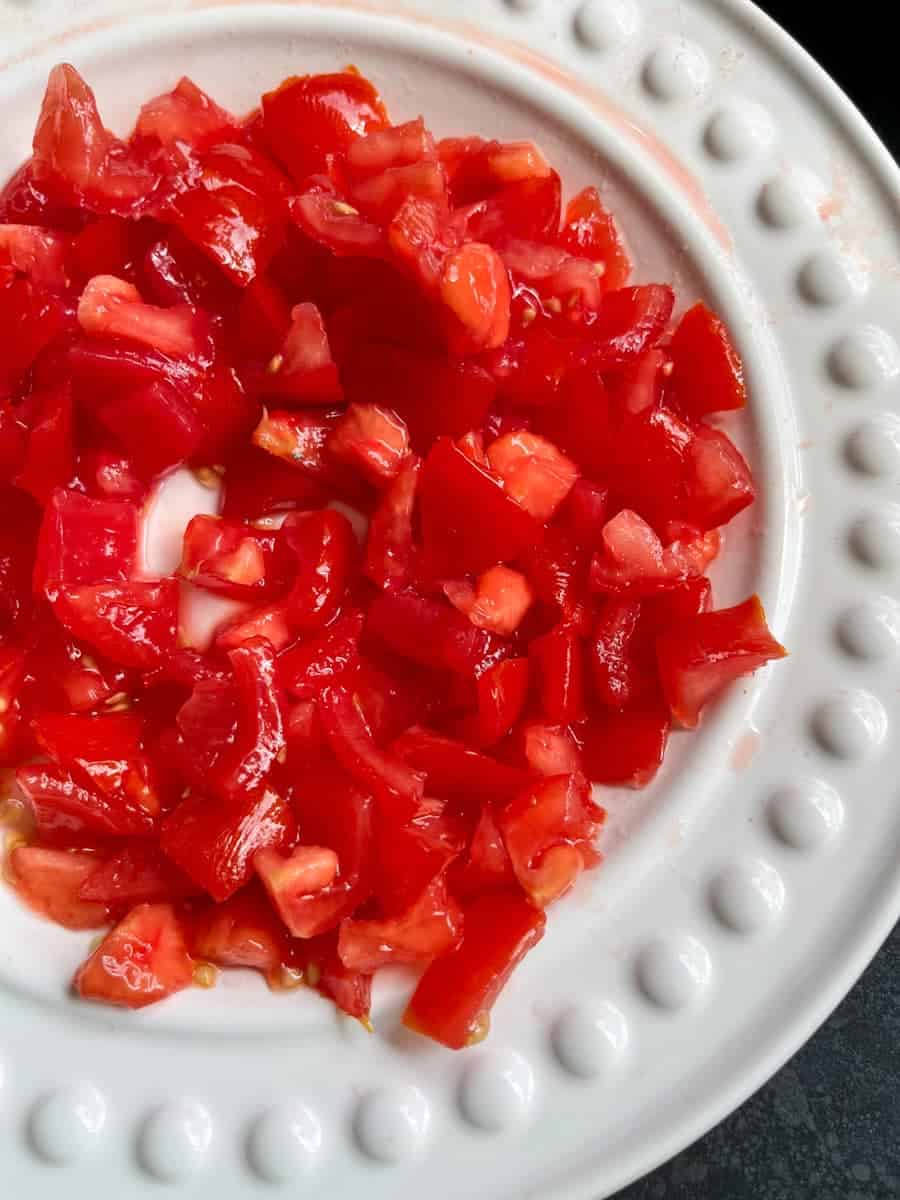 a white plate of diced fresh tomatoes.
