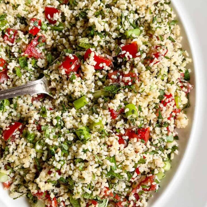 a Tabbouleh salad with chopped tomatoes, freshly chopped herbs and spring onions on a white plate.