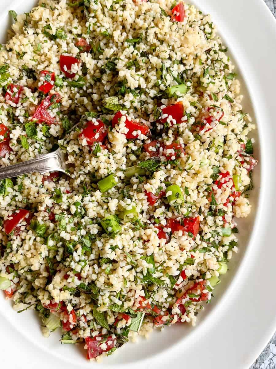 a Tabbouleh salad with chopped tomatoes, freshly chopped herbs and spring onions on a white plate.