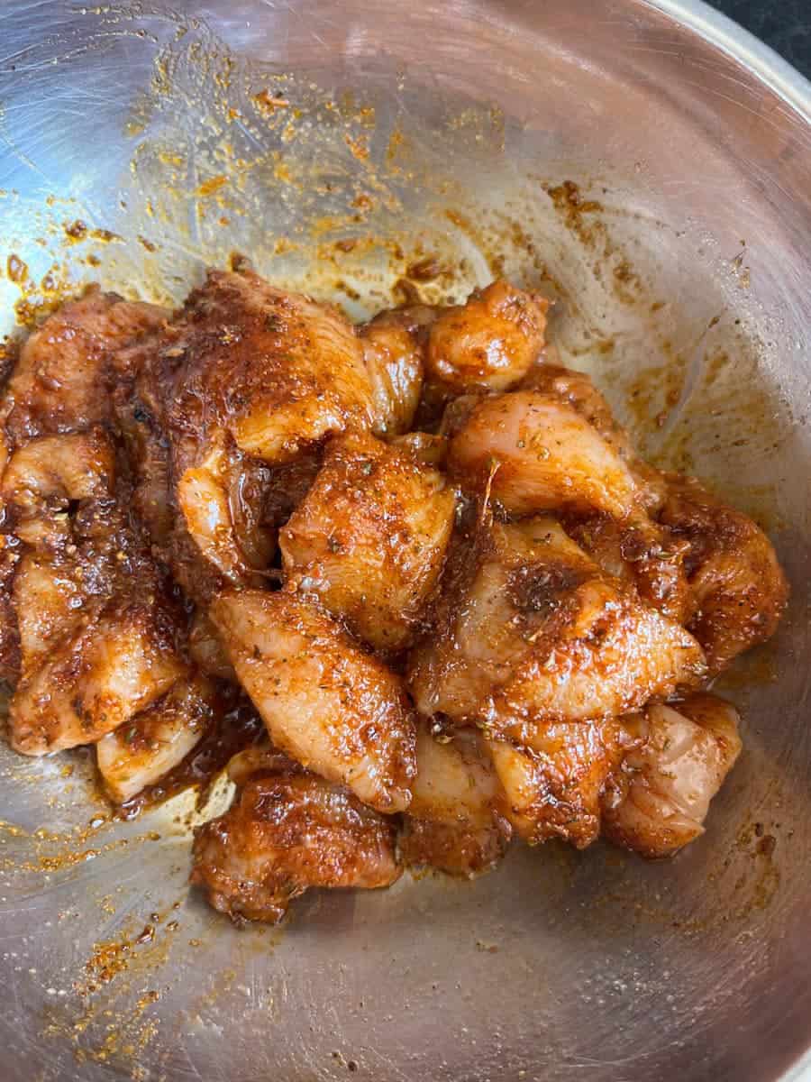 a silver bowl of raw chicken pieces coated in a Fajita spice mix.