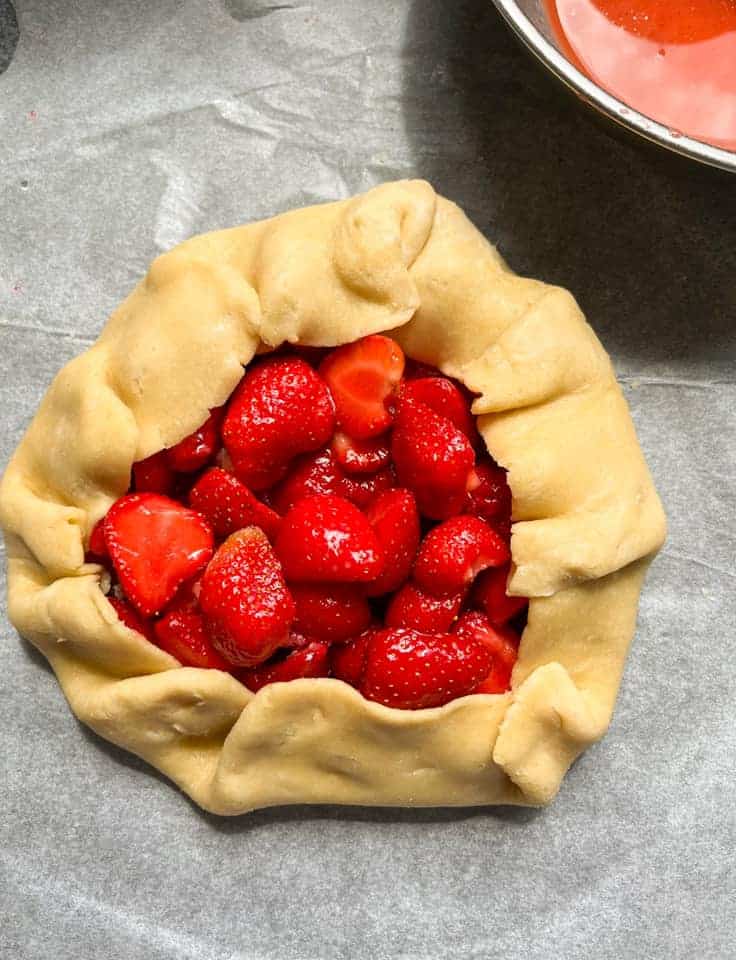 An unbaked strawberry galette on a piece of baking parchment.