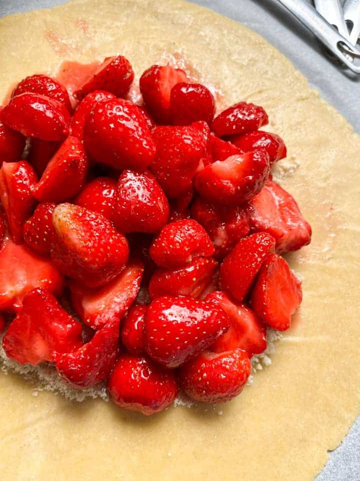 A circle of pie dough topped with fresh strawberries.