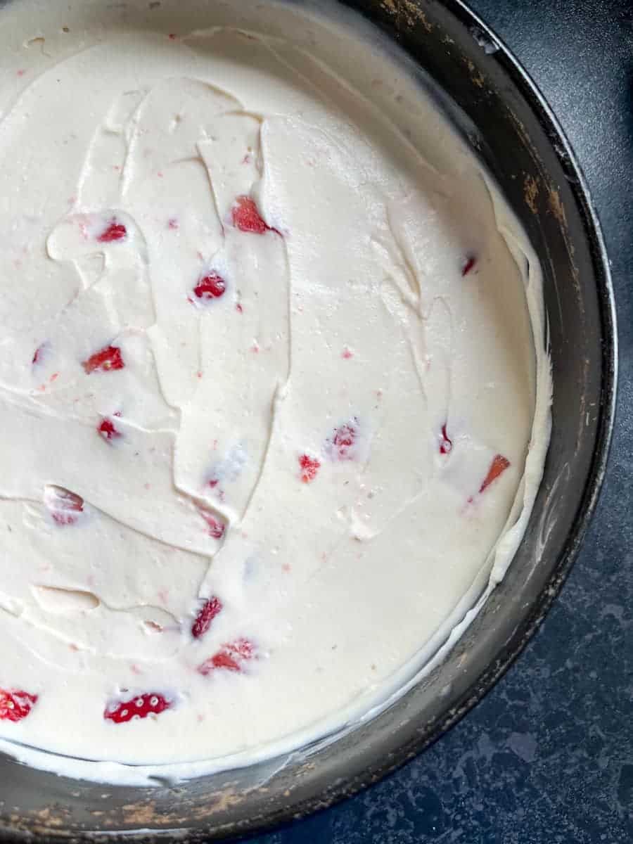 A no bake strawberry cheesecake in a round cake tin.