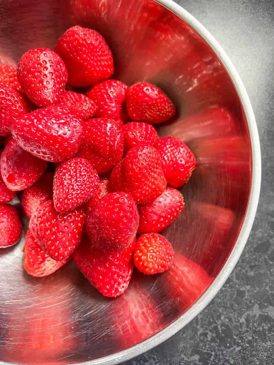 A silver bowl of halved strawberries.