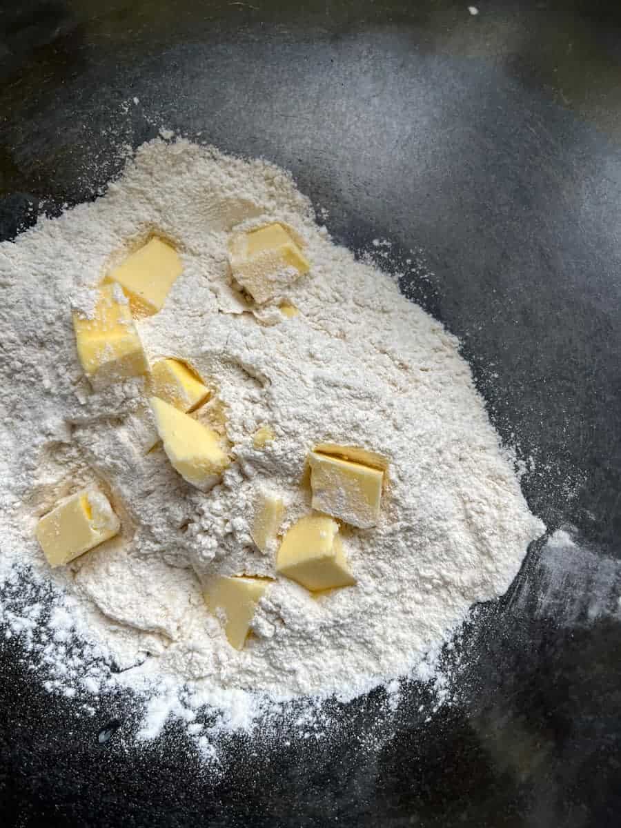 A glass mixing bowl of flour and cold diced butter.