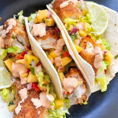three tacos with breadcrumbed fish fillets, cubed mango, red onion, shredded lettuce and drizzled with chipotle sauce.
