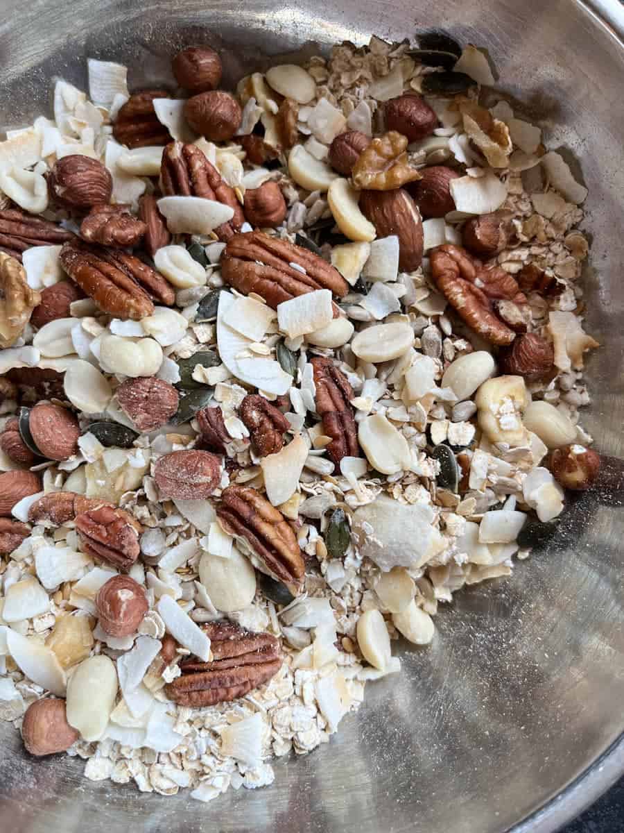 A silver bowl of oats, mixed nuts and seeds.