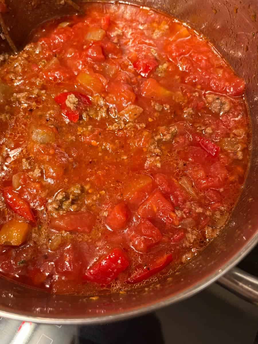 A silver pan of chilli con carne simmering on a hob.