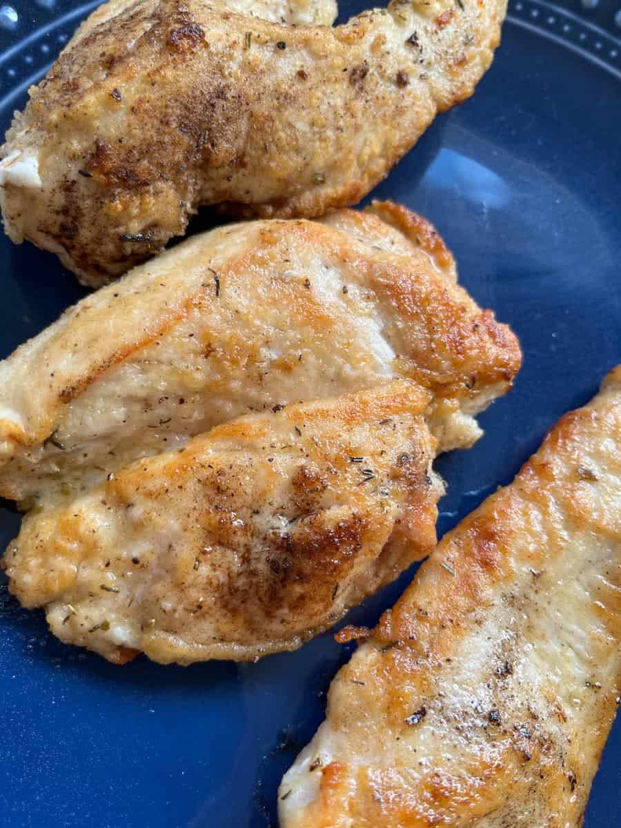 cooked chicken breasts on a blue plate.