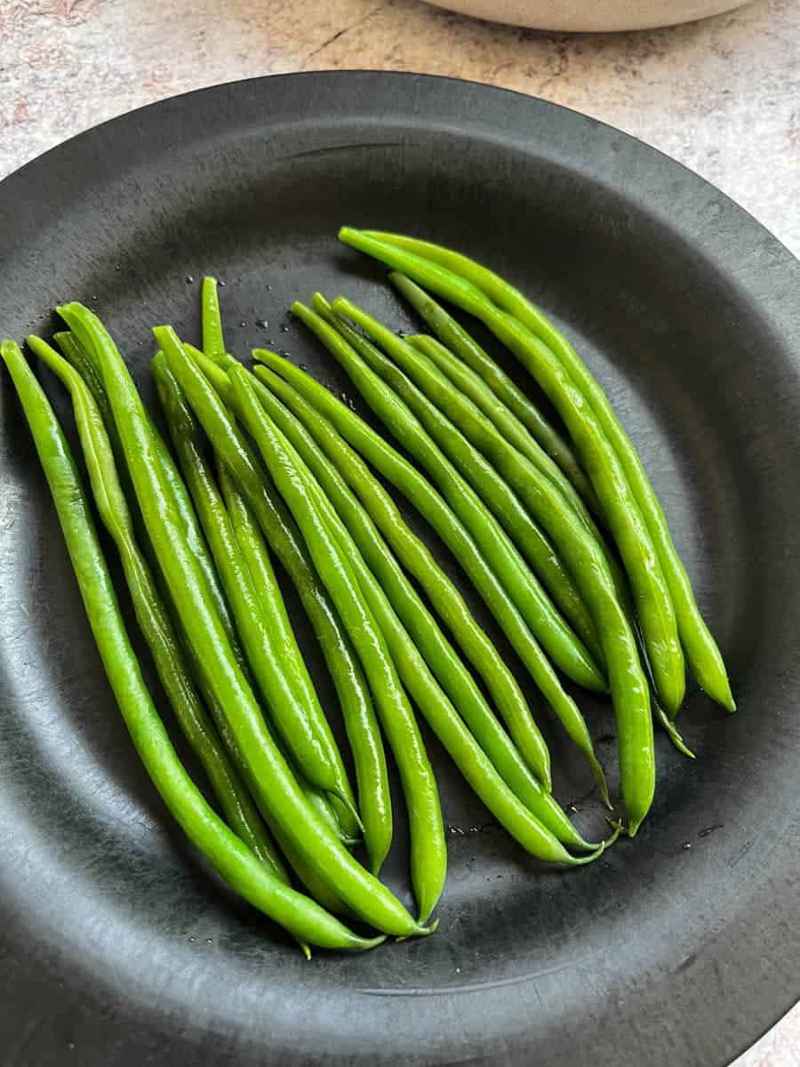 a black plate of green beans.