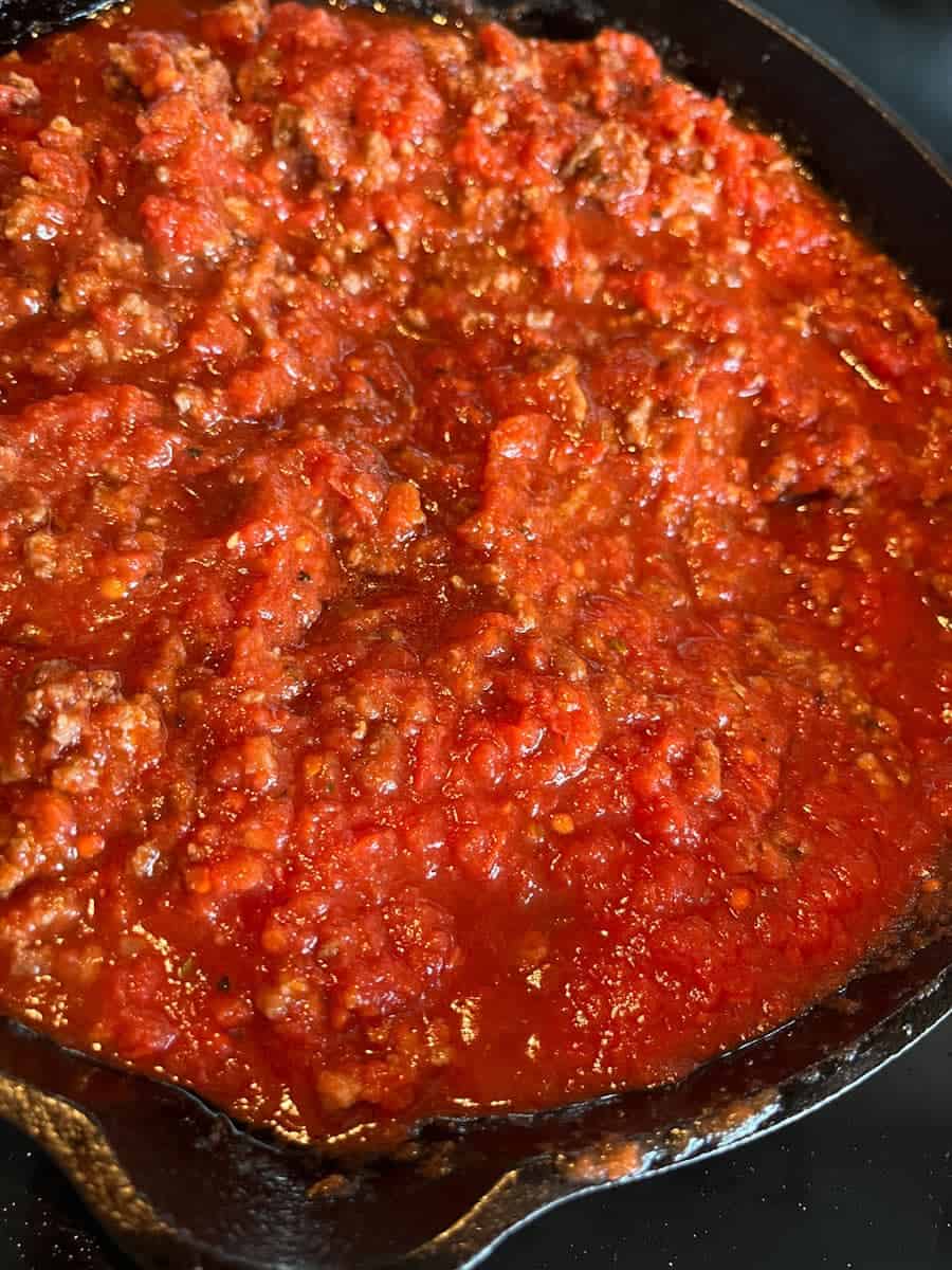 Ragu sauce cooking in a black skillet.