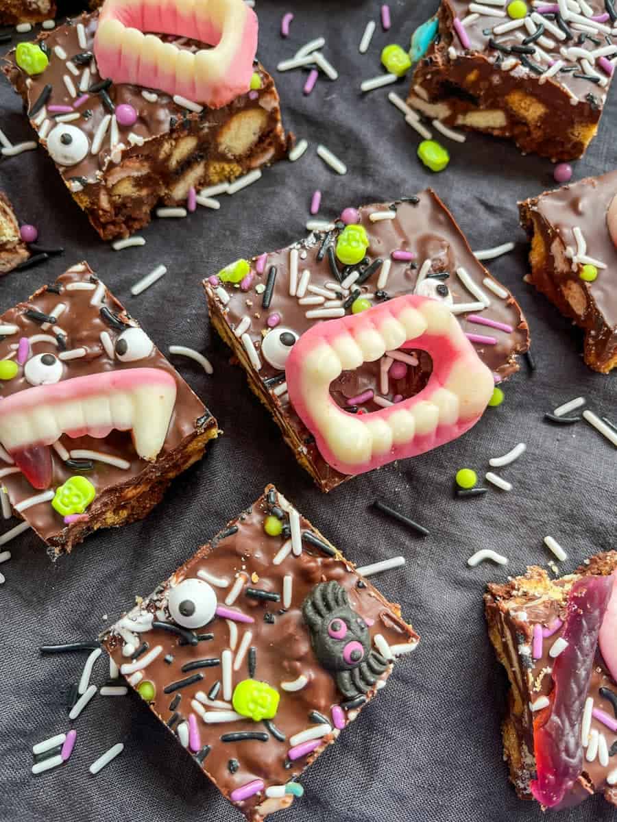Rocky road bars topped with Halloween candy eyes, candy teeth and green, purple, white and black sprinkles.